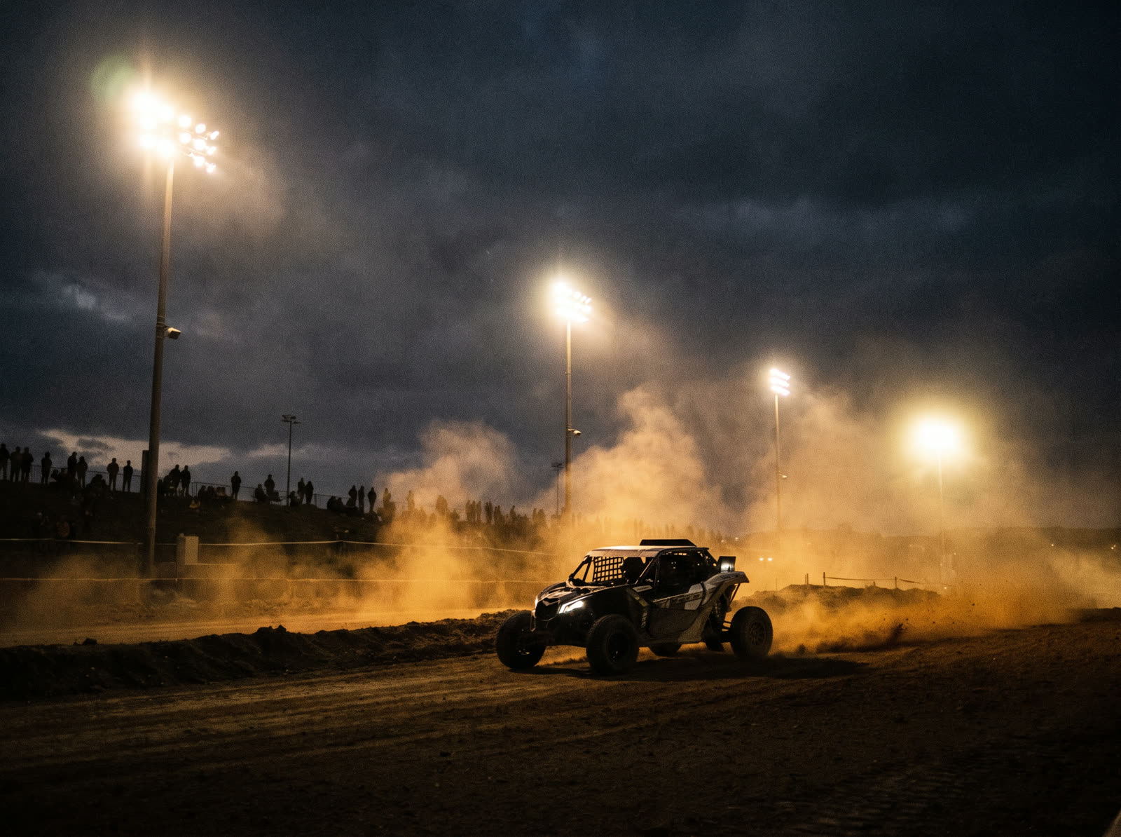 An off-road buggy racing under stadium floodlights at night
