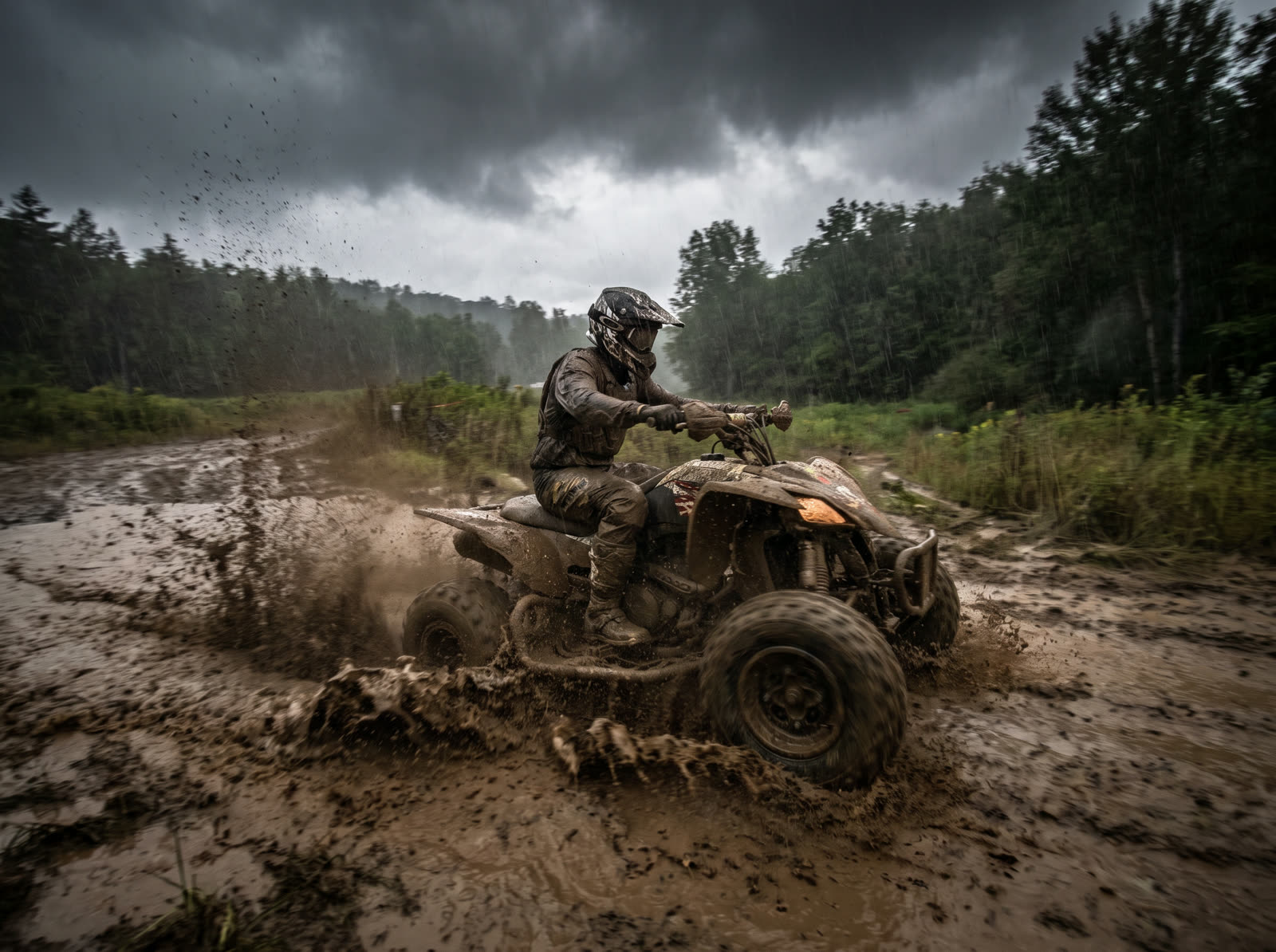 A quad bike blasting through deep mud in heavy rain